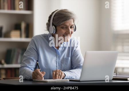 Happy middle aged woman studying on online lecture. Stock Photo