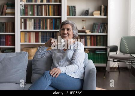 Portrait of smiling old senior woman relaxing on cozy sofa. Stock Photo