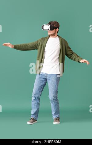Young man with virtual reality glasses on green background Stock Photo