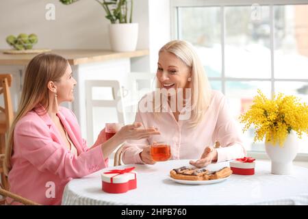 Young woman with her mother drinking tea in kitchen on holiday Stock Photo
