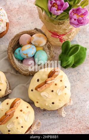 Tasty Easter cakes and nest with eggs on light background Stock Photo