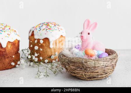 Nest with Easter bunny, eggs and cakes on table Stock Photo