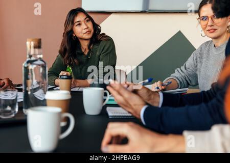 Colleagues having a meeting in a boardroom. Group of multicultural businesspeople having an important discussion during their morning briefing. Young Stock Photo