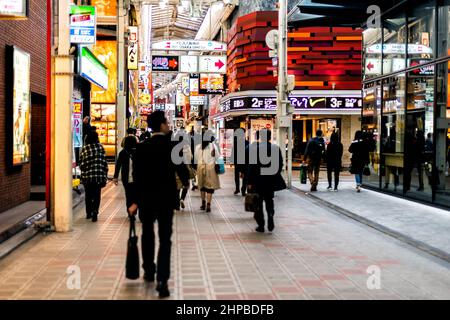 Osaka, Japan - April 13, 2019: Inside covered arcade street road shopping center with people businessman salaryman walking by stores shops Stock Photo