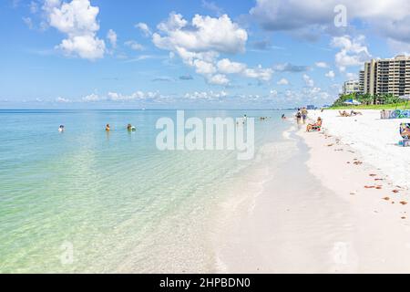 Naples, USA - August 10, 2021: Access beach in Naples Southwest Florida with people relaxing in water on summer sunny day with blue sky on gulf coast Stock Photo