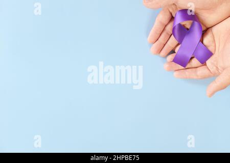 Top view of male hands holding purple ribbon color. Testicular, pancreatic cancer, epilepsy, leiomyosarcoma, lupus, Alzheimer's disease, Hodgkin Stock Photo