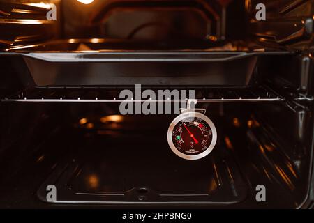 Measuring internal temperature of oven baked chicken. Meat / instant-read  thermometer to measure food safe temperature. Whole chicken in black pan  Stock Photo - Alamy