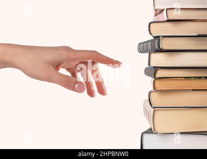 Woman hand selecting or pointing to book from stack isolated on white background. Book choice for reading. High quality photo Stock Photo