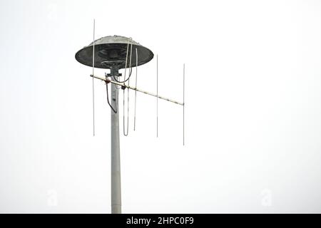 Pneumatic motor Siren, German E57, alarm for fire warning, natural disasters or attacks on a high pole that is also used for an antenna, light gray sk Stock Photo