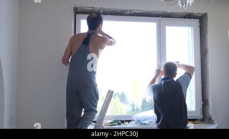 Dismantling and installation of a window in an apartment by two workers: Moscow, Russia - August 17, 2021. Stock Photo