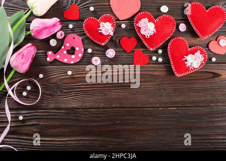 Sewed handmade fabric hearts tulips and ribbon for valentine day on dark wooden background with copy space Stock Photo