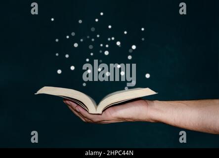 Man holding magic book with hand Stock Photo