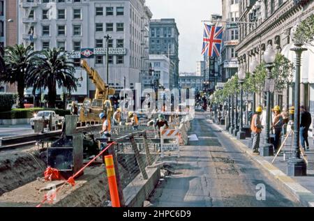 Construction workers relaying the cable car tracks in Powell Street, San Francisco, California, USA in 1980 – in this view looking southwards downhill at Union Square. The Powell Street cable car lines were originally built by the Ferries & Cliff House Railway Company, which started construction in 1887 after winning several franchises for cable car operation – a vintage 1980s photograph. Stock Photo