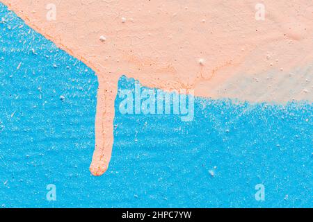 Macro close-up of a wall spray painted with light blue & sandy tan color. Abstract textured splattered graffiti background. Splashes and drip. Stock Photo