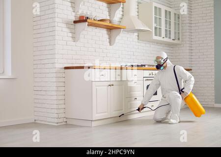 Pest control exterminator spraying chemical to get rid of insects inside the house Stock Photo