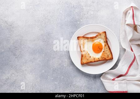 Breakfast on Valentines Day. Heart shaped egg with toast and microgreens on light grey background, breakfast table top. Valentines day breakfast. Top Stock Photo
