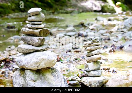 Two rock stacks in a creek bed. Piles of stacked rocks, balancing on big rocks in a bed of a wild stream. Rocks laid flat upon each other. Stock Photo