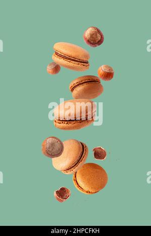 nutty macaroons and hazelnuts with crumbs flying on a green back Stock Photo