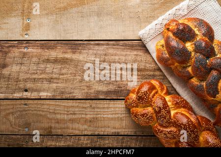 Shabbat Shalom. Bread challah with sesame seeds and poppy seeds on wooden background. Traditional jewish bread for Shabbat and Holidays. Rustic concep Stock Photo