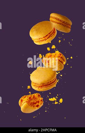 yellow macaroons with crumbs flying on a purple background Stock Photo