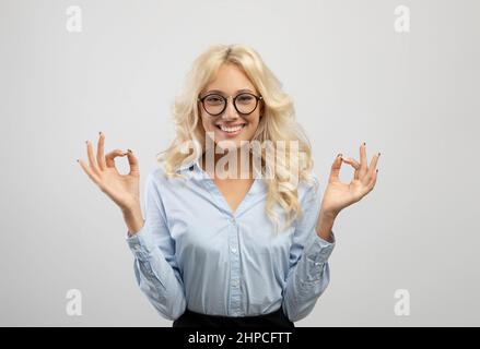 Coping with stress at work. Young businesswoman meditating after busy day, doing breathing exercises and smiling Stock Photo