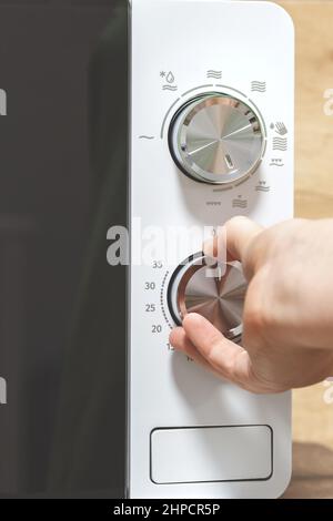 hand using an oven.  Girl Adjusting Temperature Of Microwave Oven.Using microwave oven. power regulator, temperature control Stock Photo