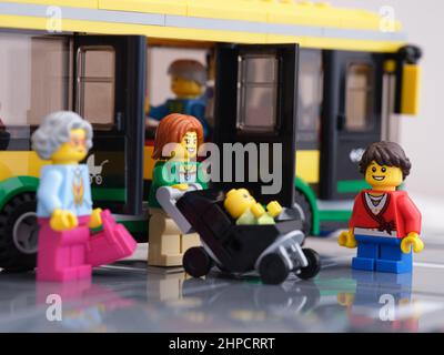 Tambov, Russian Federation - February 16, 2022 A Lego woman minifigure exiting from a bus with a stroller with a child in it while other Lego minifigu Stock Photo