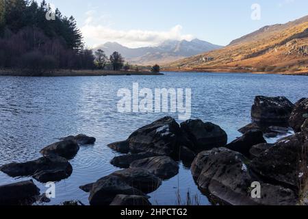 An image of a snow capped Snowdown in the background taken from Llynnau Mymbyr in Capel Curig in Snowdonia National Park Stock Photo