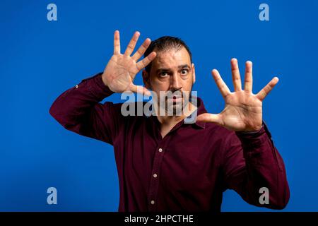 Man with scared expression on his face making frightened gesture with his palms as if trying to defend himself from someone Stock Photo