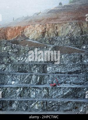 Red drilling machine on a bench of diabase quarry in misty morning Stock Photo
