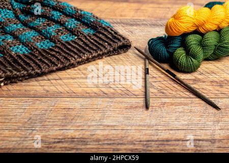 Blue and brown winter hat with a checkered pattern on a wood background closeup. Stock Photo