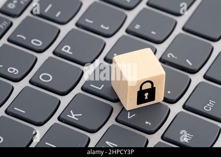 Wooden block with lock graphic on computer keyboard. Computer security concept. Stock Photo