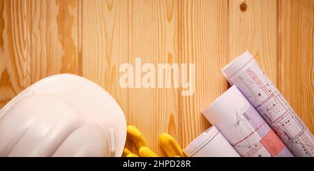 White hardhat, yellow gloves and rolled drawings Stock Photo