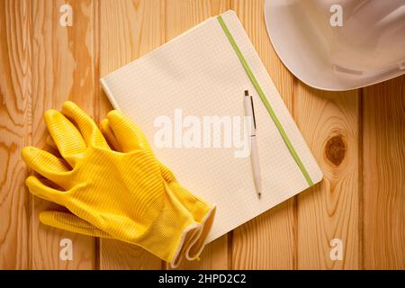 White hardhat, yellow gloves and blank notepad with pen Stock Photo