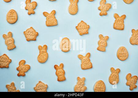 Bunny shaped sugar cookies with Easter chocolate eggs and flower background. Happy Easter Stock Photo