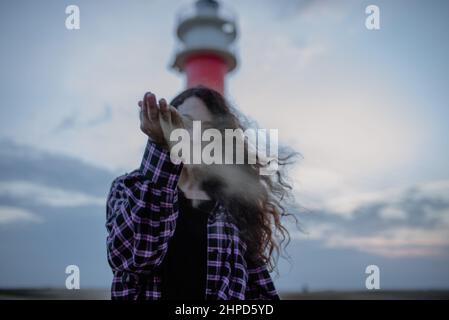 Woman dropping a handful of sand in front of her face. Time and lost Stock Photo