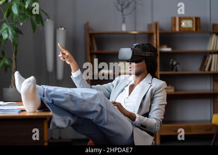 Excited african american business woman testing VR glasses, using virtual reality for remote work Stock Photo