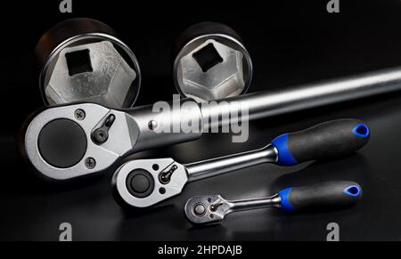 Closeup of metal ratchets or interchangeable hex sockets on black background. Steel ratcheting socket wrenches or replaceable hexagon tightening tools. Stock Photo