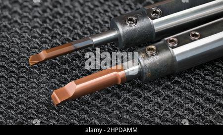 Replaceable carbide boring knives with round shank on black net background. Steel cutting tool to working inside small holes in metal holders. Turning. Stock Photo