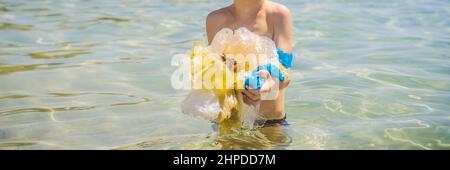 Boy collects packages from the beautiful turquoise sea. Paradise beach pollution. Problem of spilled rubbish trash garbage on the beach sand caused by Stock Photo