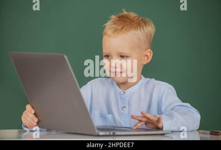 School boy learn lesson sitting at desk, studying online e-learning use internet. Genius child programming, computer training. Stock Photo