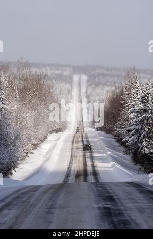 uebec 216 road, in the region of Chaudière-Appalaches, in winter with a large panoramic view on the snowed forest bordering the partial snowed road. Stock Photo