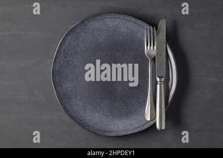 Dark plate on a dark concrete background with cutlery Stock Photo