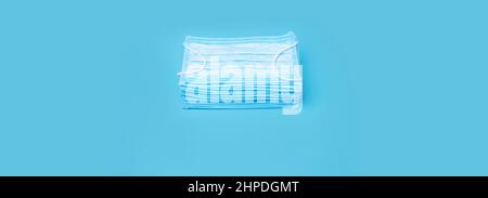 Design background medical masks in stack. Stack of surgical masks on blue background. Pile of face masks medical banner health and medicine design Stock Photo