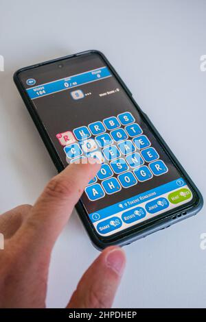 Wordle game on a smart phone with blue letters and dark background Stock Photo