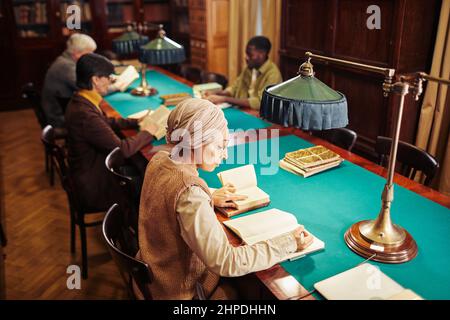 High angle portrait of Muslim young woman studying in classic library interior, copy space Stock Photo