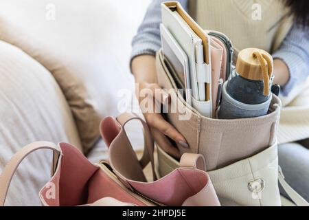 Closeup female hands shifting modern comfortable storage felt organizer into leather handbag Stock Photo