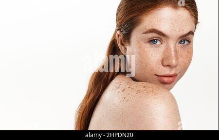 Body and Spa concept. Beautiful redhead woman plus size, looking behind shoulder and smiling. Chubby girl with clear healthy facial skin after shower Stock Photo