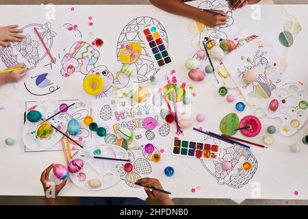 Background image of children painting Easter eggs and coloring books on table while enjoying art and craft class together Stock Photo