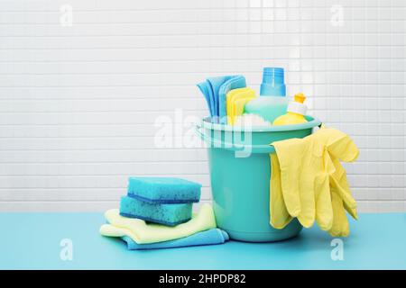 Cleaners and detergents in bucket, accessories for cleaning various surfaces and rooms blue background Stock Photo